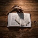 הזמן לשינוי אמיתי - אלול A shofar and open book on a rustic wooden table, symbolizing Jewish traditions.