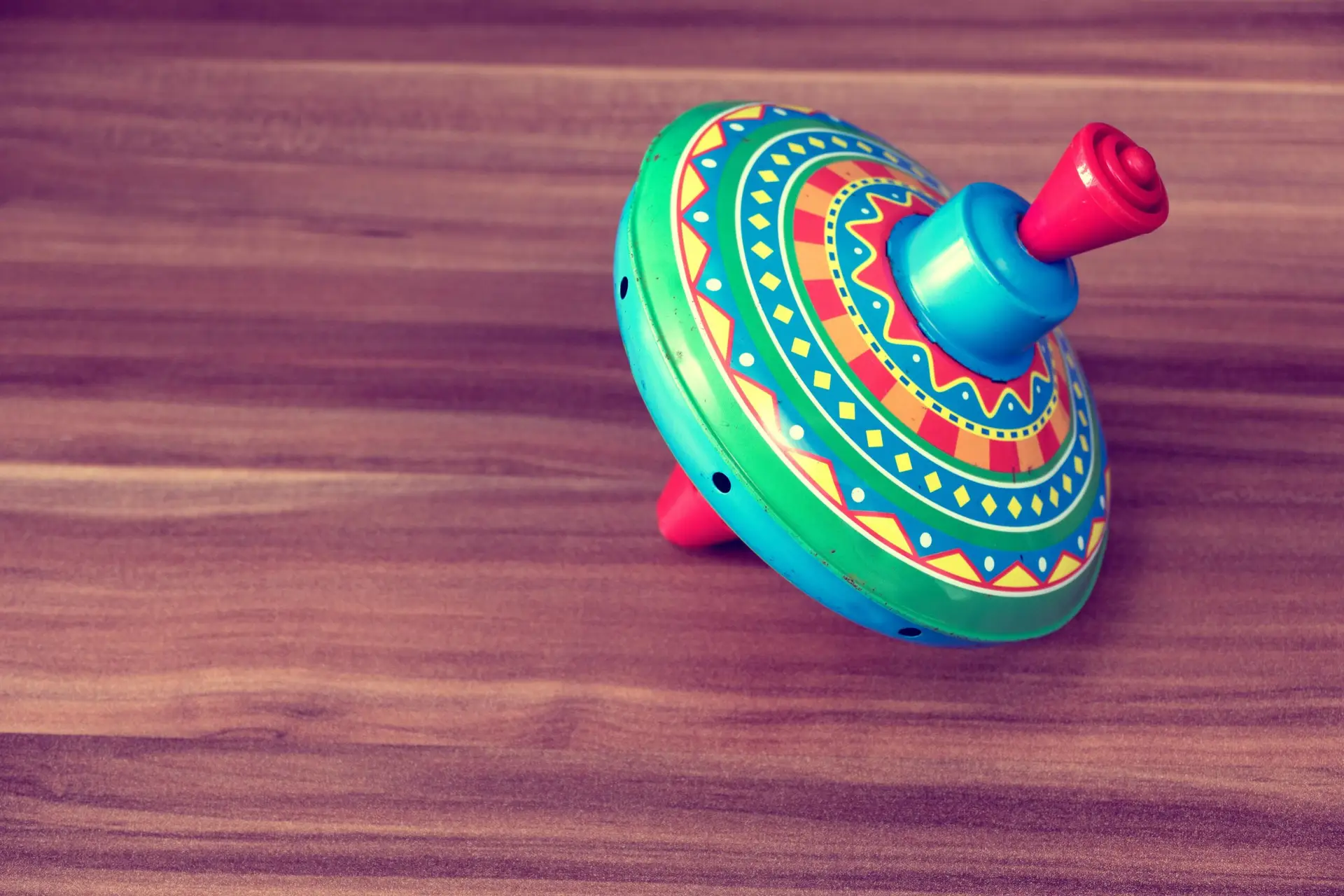 חוויות ילדות Brightly colored vintage spinning top toy on a wooden table, evoking childhood memories and playful nostalgia.