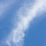 A tranquil scene of soft, white clouds drifting across a vibrant blue sky.