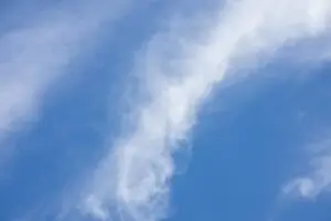 A tranquil scene of soft, white clouds drifting across a vibrant blue sky.