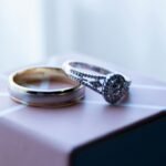 Close-up of luxurious diamond and gold wedding rings on a decorative box.