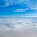 A stunning aerial view of fluffy clouds under a bright blue sky, captured in daylight.